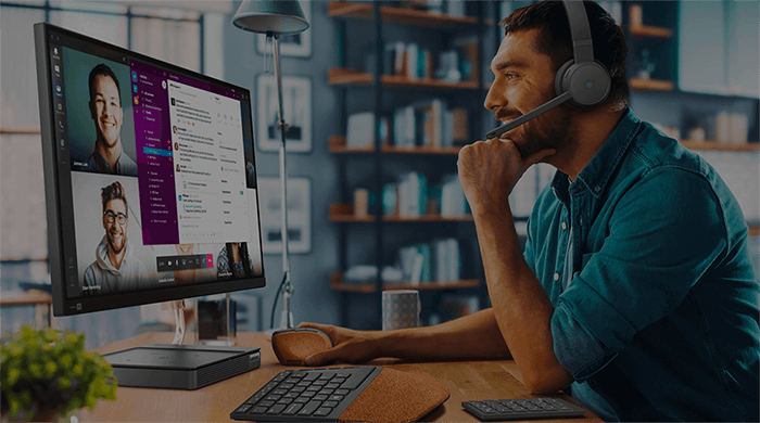 Dettaglio di un uomo a lavoro in smart working davanti a un monitor e con indosso delle cuffie wireless con microfono.
